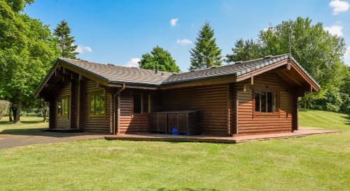 a log cabin sitting on top of a lush green field at Pinecroft Lodges in Ingleton 