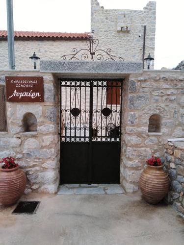 una entrada a un edificio de piedra con una puerta negra en Παραδοσιακός Ξενώνας Λυμπέρη, en Koíta