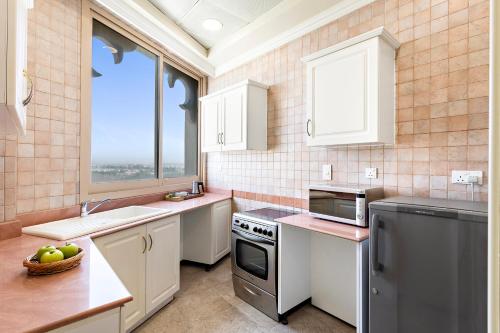a kitchen with white cabinets and a sink and a window at Al Hamra Residence in Ras al Khaimah