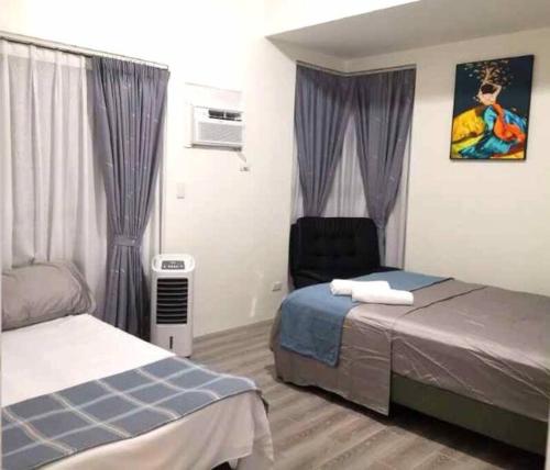 a bedroom with two beds and a chair in it at Amani Grand Luxury Big Suite/Near Airport/3beds in Davao City