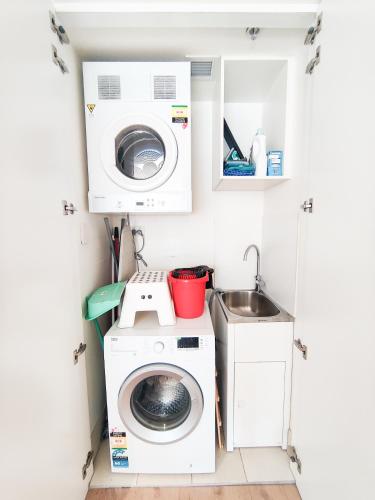a small kitchen with a washing machine and a sink at Cozy Apartment at St Leonard in Sydney