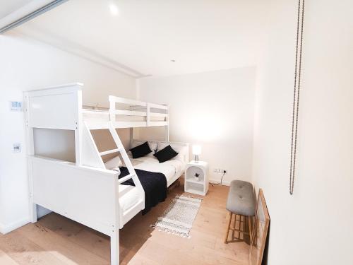 Cozy Apartment at St Leonard في سيدني: غرفة نوم بيضاء مع سرير بطابقين وأريكة