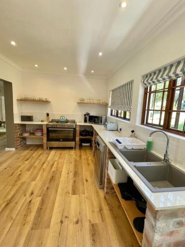 una grande cucina con pavimenti in legno e un grande lavandino di Brummer House - Living The Breede a Malgas