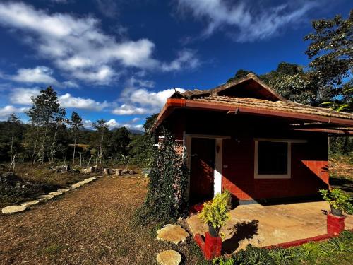 een klein rood huis met een pad ernaast bij A Madan Homestay in Napoklu