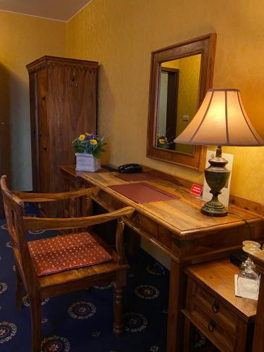 a desk with a lamp and a chair and a mirror at Hotel Zameczek in Książ Wielki