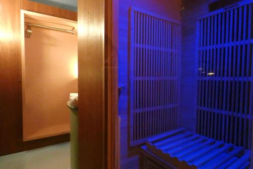 - une salle de bains avec un banc dans une chambre dotée de lumières bleues dans l'établissement Le Neptune - Splendide - Sauna - Saint-Germain, à Paris