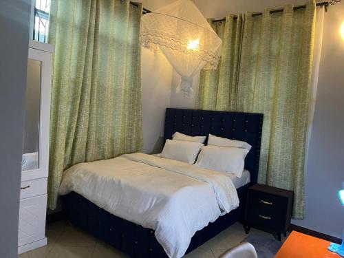 sypialnia z łóżkiem z zielonymi zasłonami i żyrandolem w obiekcie Stunning, Romantic and Luxurious Apartment w mieście Dar es Salaam