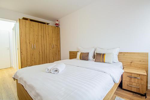 1 dormitorio con 1 cama blanca grande y armarios de madera en MO Apartments Spac, en Brasov