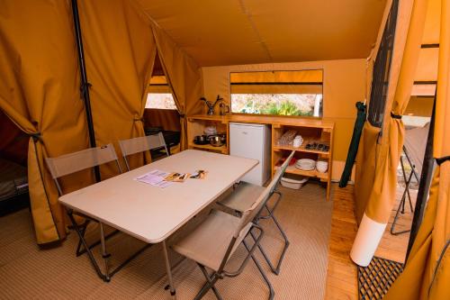 uma sala de jantar com uma mesa e cadeiras numa tenda em Camping Les Peupliers du Lac Onlycamp em Chindrieux