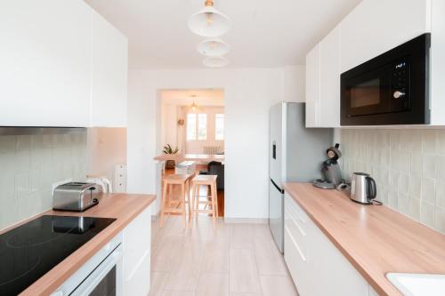 une cuisine avec des armoires blanches et un comptoir dans l'établissement BonaBonheur - T3Bis - Havre de Paix Toulousain, à Toulouse