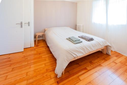 a white bed in a room with a wooden floor at BonaBonheur in Toulouse