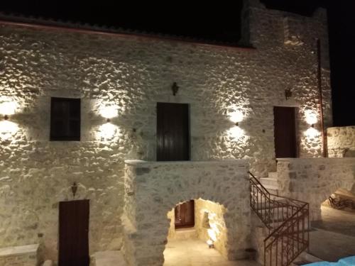 a stone building with a brick wall with lights at Παραδοσιακός Ξενώνας Λυμπέρη in Koíta
