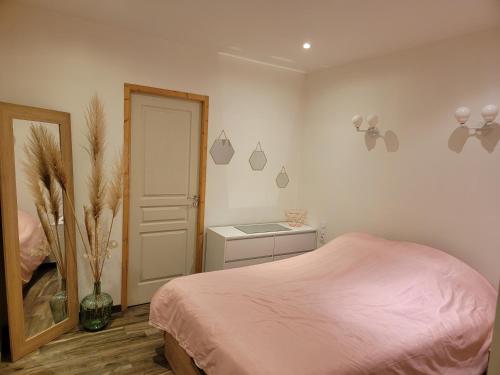 a bedroom with a pink bed and a table at Appartement au cœur des Albères in Le Boulou