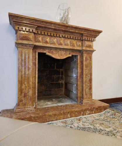 an antique fireplace with a stone mantle on a rug at La Famosa Dimora Ambasciatore in San Marino