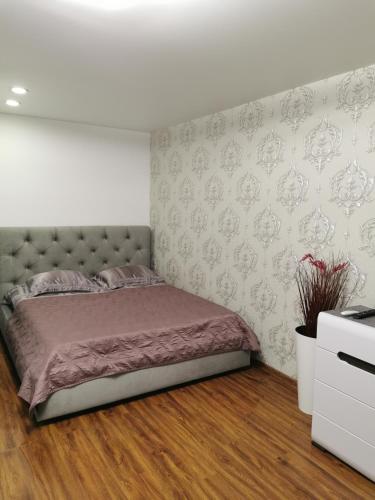 a bedroom with a bed in a room with a wall at Studio Apartment in the center in Shostka