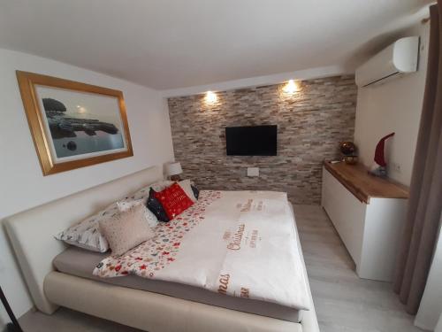 a bedroom with a bed and a tv on a brick wall at Apartment Ena in Stara Novalja
