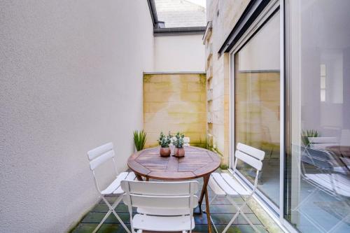 d'une terrasse avec une table en bois et des chaises blanches. dans l'établissement Beautiful apartment Bordeaux with private terrace, à Bordeaux