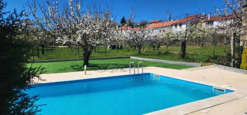 a blue swimming pool in a yard with trees at CASA DO ESTÁBULO - Vila Garcia - Trancoso in Carigas