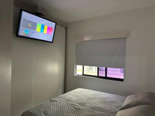 1 dormitorio con 1 cama y TV en la pared en Simplicidade e aconchego, en Itapema