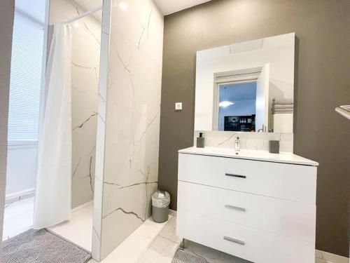 een badkamer met een witte wastafel en een spiegel bij Studio Jungle N2 in Alençon