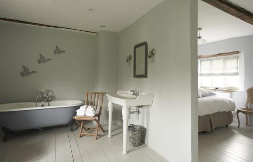 a bathroom with a tub and a sink and a bed at Sky in Sharrington