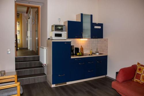 a kitchen with blue cabinets and a microwave on top at Ferienwohnung Hirschgrundblick in Oberlungwitz