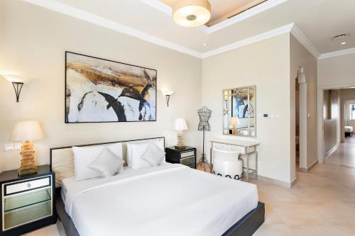 a white bedroom with a large bed and a bathroom at Al Hamra Residence in Ras al Khaimah