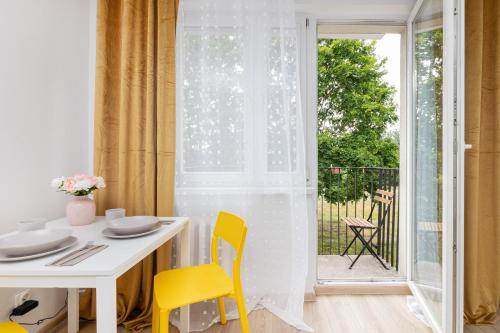 a white dining room with a white table and yellow chairs at Sunny Studio Opolska with Balcony in Gdańsk by Renters in Gdańsk