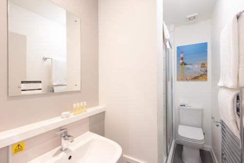 a bathroom with a sink and a toilet and a mirror at The Burlington Hotel in Eastbourne