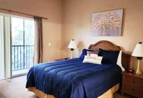 Un dormitorio con una cama azul y una ventana en Bahama Bay Resort & Spa - Deluxe Condo Apartments, en Kissimmee