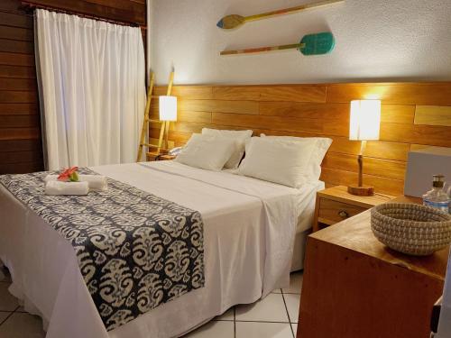 um quarto com uma grande cama branca e paredes de madeira em Pousada Estrela do Mar Noronha em Fernando de Noronha