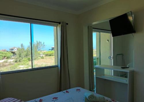 a bedroom with a bed and a window with a view at Pousada dos Reis in Barra de Ibiraquera