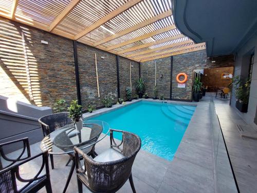 an indoor swimming pool with a table and chairs at Hotel Santiago Patio Bellavista in Santiago