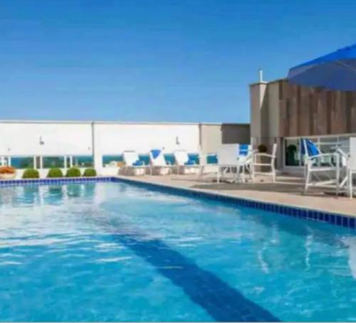a large swimming pool with blue chairs and chairs at Macaé Ramada Flat RJ in Macaé
