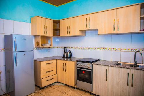 a kitchen with wooden cabinets and a white refrigerator at RIGTH Homes in Kigali
