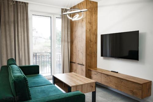 ein Wohnzimmer mit einem grünen Sofa und einem TV in der Unterkunft Apartamenty Nad Potokiem koło Karpacza in Staniszów