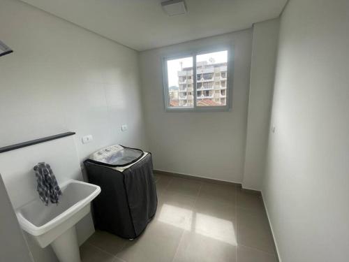 a bathroom with a sink and a toilet and a window at Lindo apartamento Ubatuba in Ubatuba