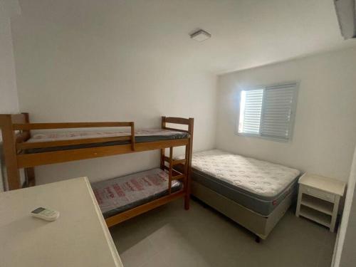 a small room with two bunk beds and a table at Lindo apartamento Ubatuba in Ubatuba