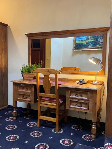 a desk with a lamp and a chair in a room at Hotel Zameczek in Książ Wielki