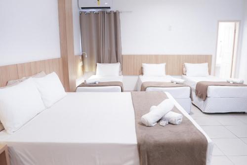 a hotel room with three beds and a couch at Pousada Areia do Forte in Cabo Frio