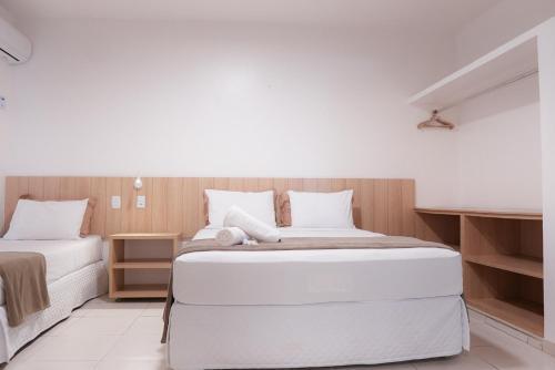 a white bedroom with two beds and wooden walls at Pousada Areia do Forte in Cabo Frio