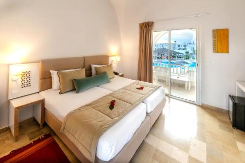 a bedroom with a large bed and a balcony at Djerba Sun Beach, Hotel & Spa in Houmt Souk