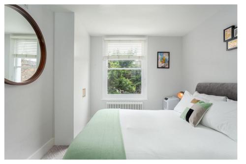 1 dormitorio con cama blanca y ventana en Chic 3BD Maisonette wRoof Terrace - Wandsworth!, en Londres