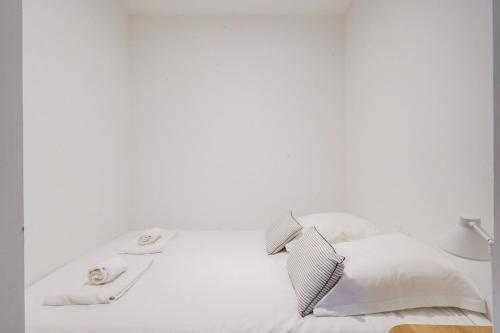 ein weißes Bett mit weißer Bettwäsche und einer Lampe in der Unterkunft Beautiful apartment in Chartrons with terrace in Bordeaux