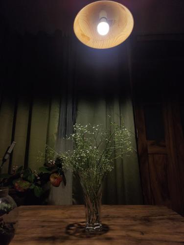eine Blumenvase, die auf einem Tisch unter einem Licht liegt in der Unterkunft Ivory Botanic Stay in Darjeeling