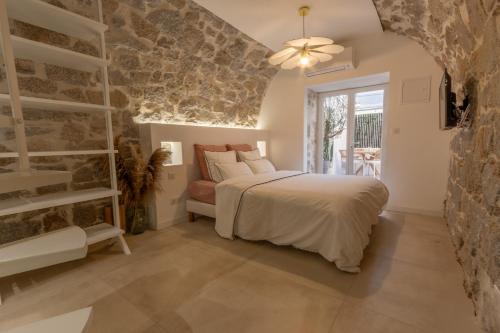 1 dormitorio con cama y pared de piedra en Le Miot - Duplex avec terrasse, en Ajaccio