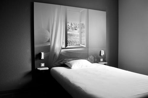 a black and white photo of a bedroom with a bed at B&B HOTEL Bordeaux Langon in Langon