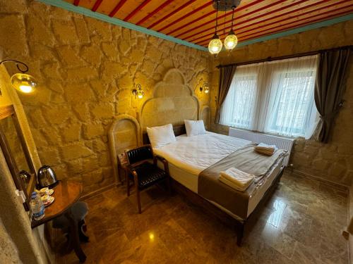 a bedroom with a large bed in a stone wall at Rustic Caves Hotel in Goreme