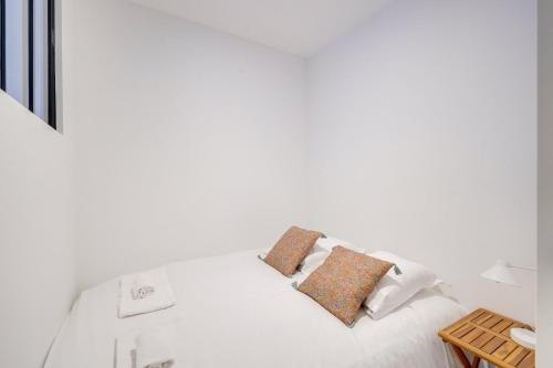 um quarto com uma cama branca com almofadas em Lovely apartment Bordaux em Bordeaux