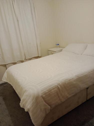 a white bed in a bedroom with a window at Milton Keynes Lettings in Milton Keynes